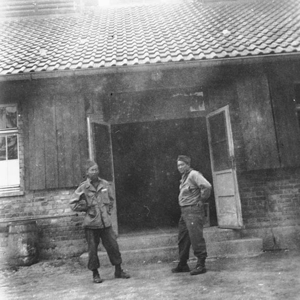 Two soldiers of the 522nd Field Artillery Battalion stand in front of the crematorium, Dachau, credit USHMM