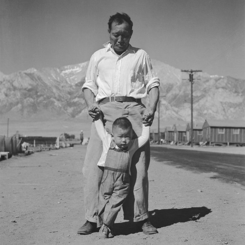 Grandfather teaching grandson to walk, Manzanar, CA, 1942, photo by Dorothea Lange