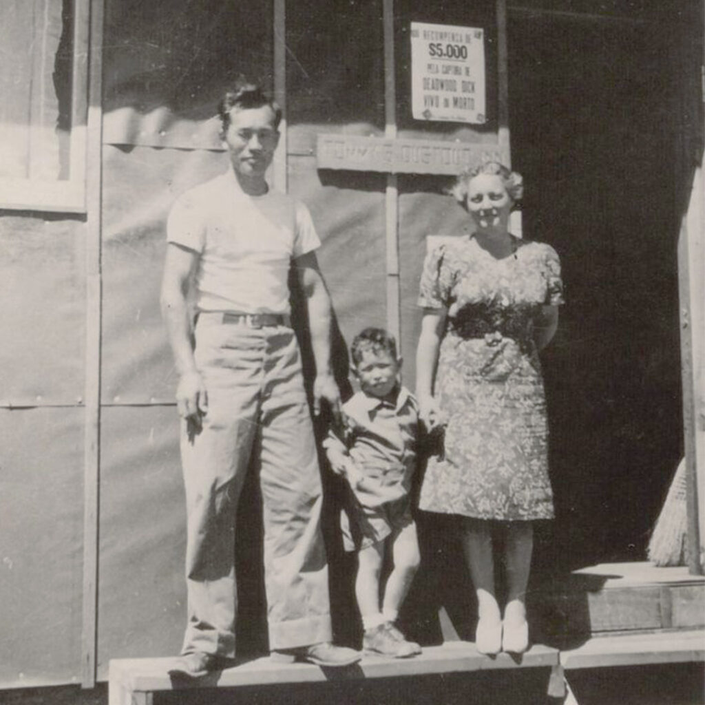 Karl, Tommy, and Elaine Yoneda in front of their barrack apartment in Manzanar, credit UCLA Library