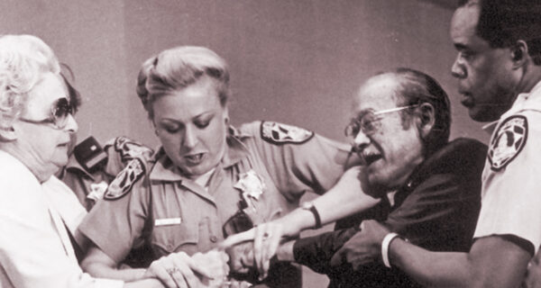 Officers assist Jim Kawaminami to stop Lillian Baker from trying to take his papers and the redress hearings, Los Angeles, 1981, credit Densho Encyclopedia