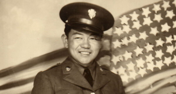 Sadao Munemori standing in front of a painted American flag