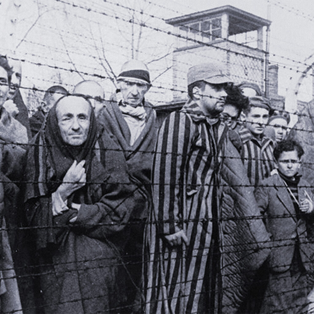 Prisoners behind barbed wire at Auschwitz.