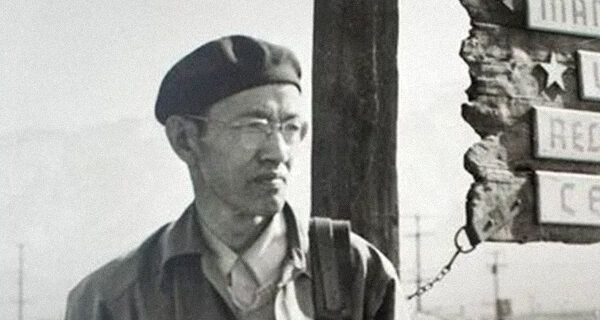 Toyo Miyatake in front of the Manzanar sign