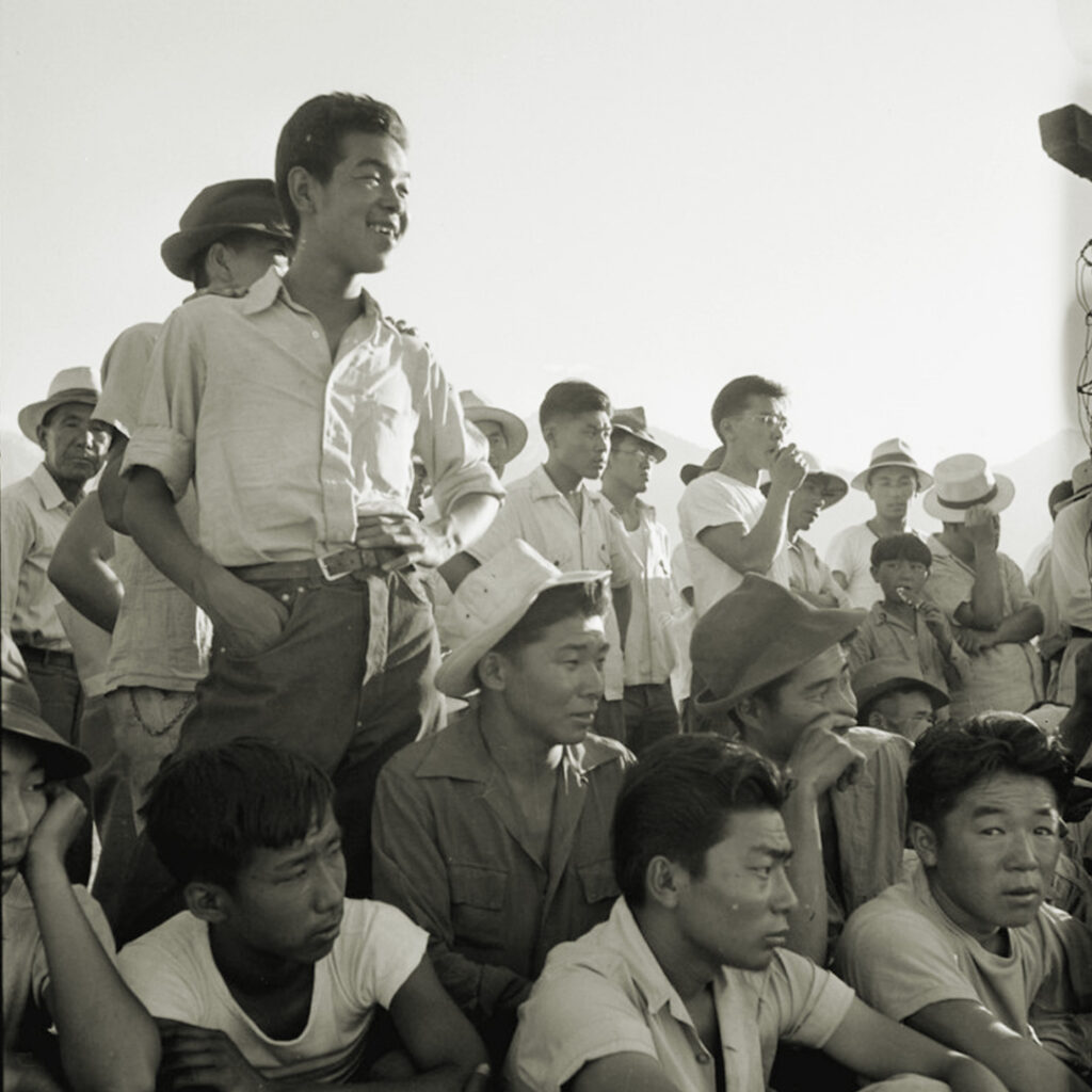 A crowd of incarcerated Japanese Americans watching baseball at Manzanar. Photo by Dorothea Lange.