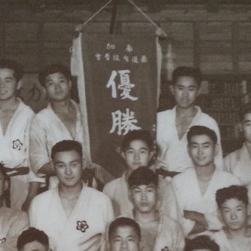 Claude Mimaki (right of the “Victory” banner) with teammates at the San Gabriel Judo Dojo, 1939.